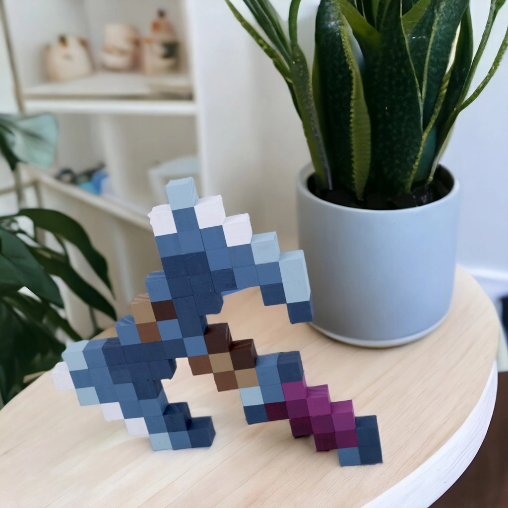 Wooden Minecraft Cursed Axe display piece on tabletop beside potted plant.