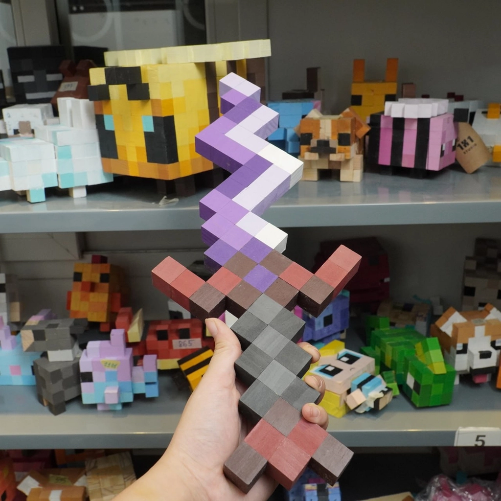Wooden Minecraft Eternal Knife collectible held in hand in front of pixel art wooden toy collection.