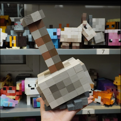 Pixel Minecraft wooden Mjolnir hammer held in hand among wooden toy shelf display.